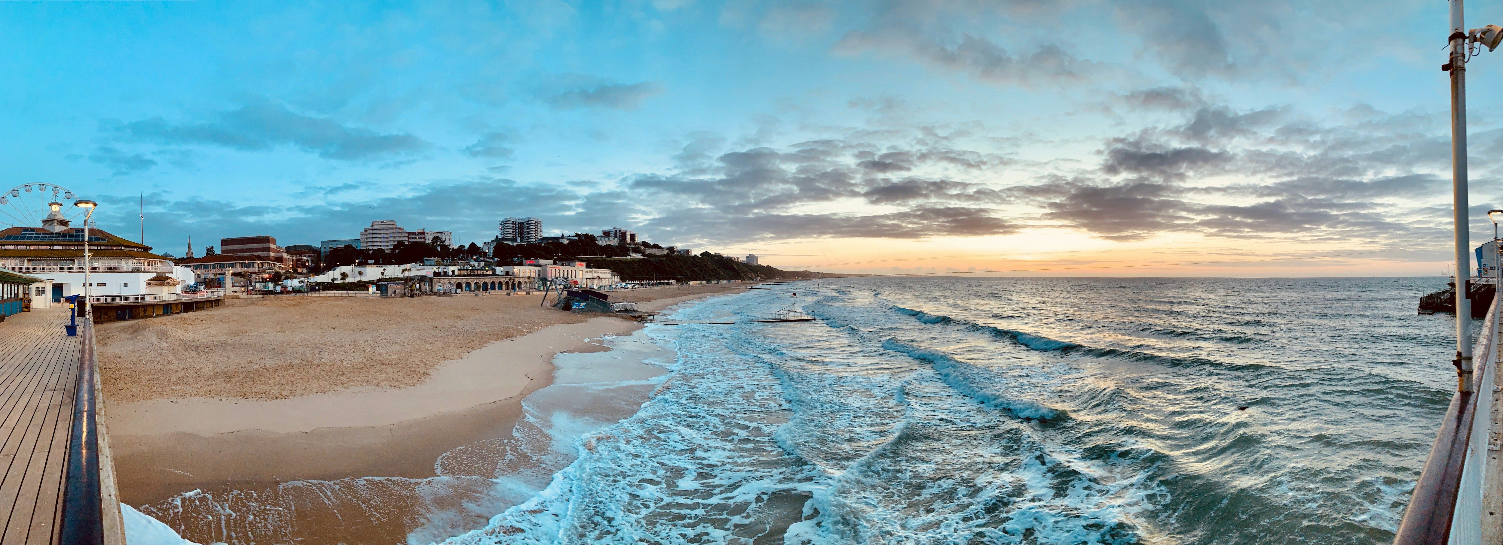 Bournemouth beach and the East Cliff at sunrise, seen from the pier, with waves running up the sand